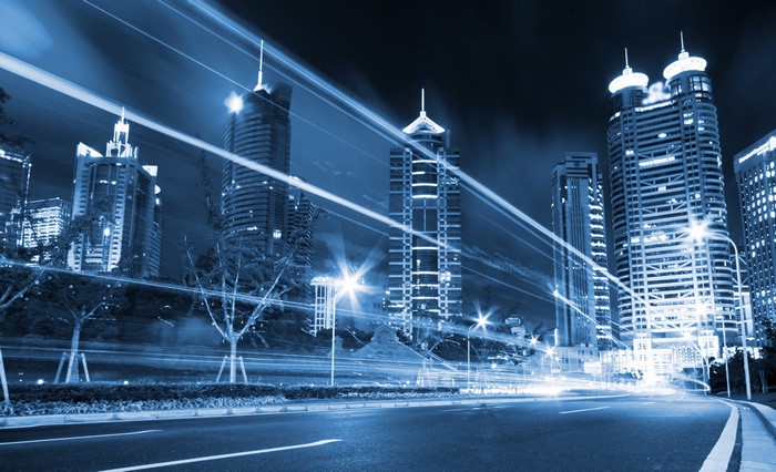Night city street with skyscrapers and light trails