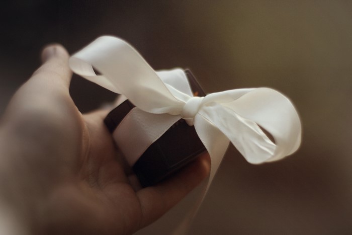 Hand holding a gift with a white ribbon