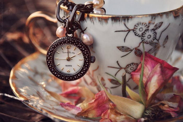 Pocket watch and teacup with dried roses