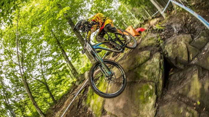 Man riding a bicycle downhill on a rocky forest path