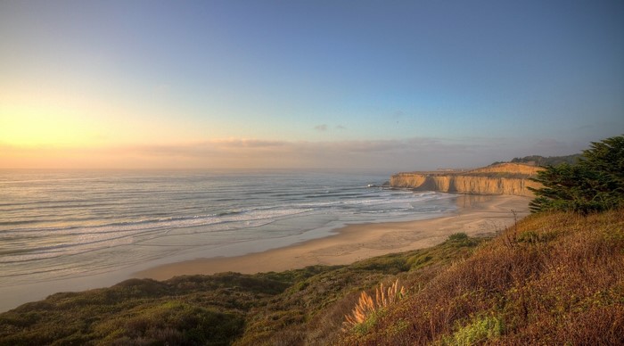 Ocean waves crash on a sandy beach at sunset