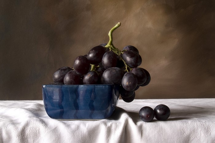 Grapes in a blue bowl on a white tablecloth