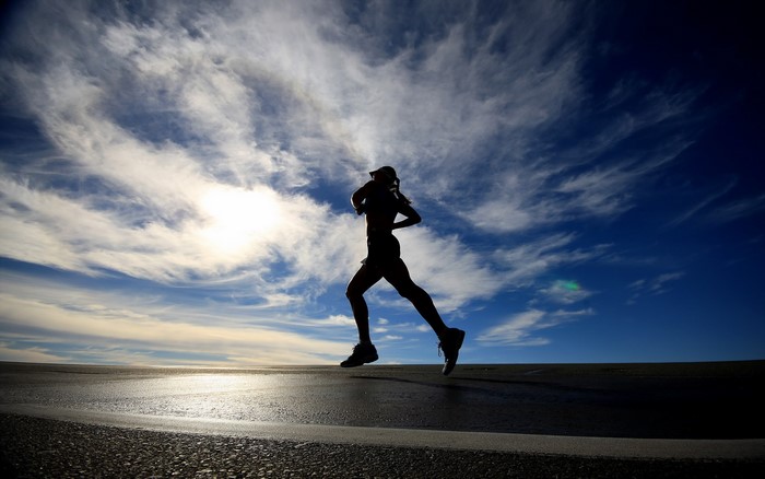 Silhouette of a runner against a cloudy sky