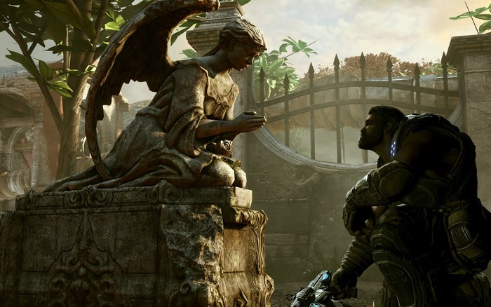 Marcus Fenix kneels before an angel statue in Gears of War
