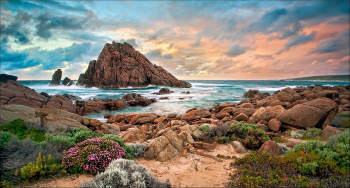 Rocky coast with large rock formations and ocean waves at sunset