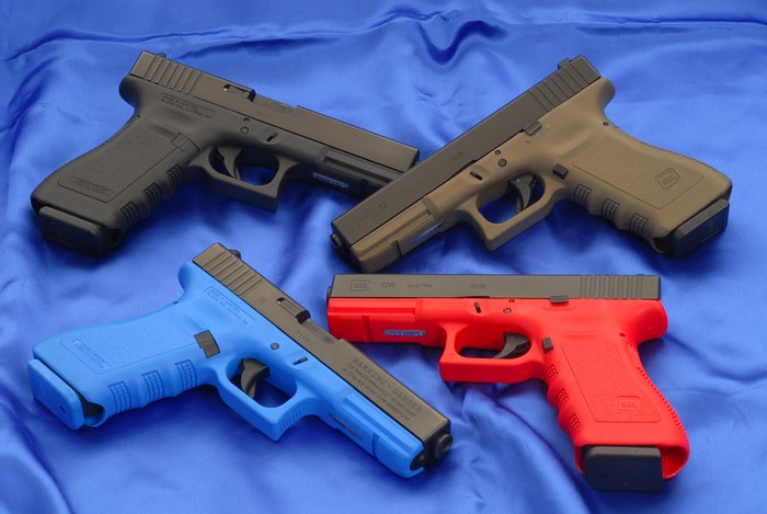 Four Glock pistols on blue fabric