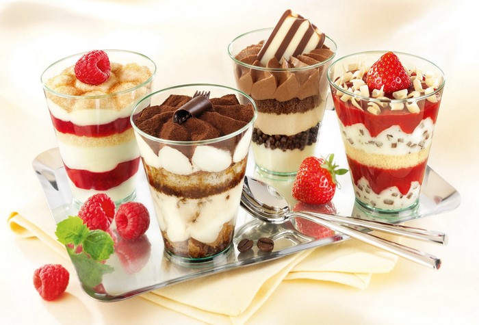 Four layered desserts with berries and chocolate on a tray