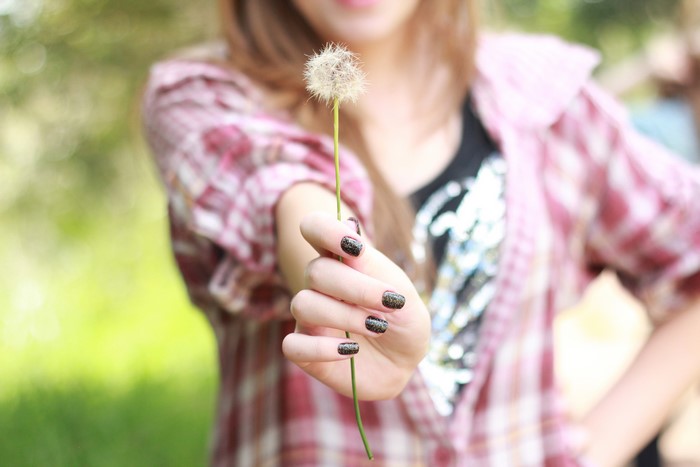 Girl holding a dandelion with glitter manicure