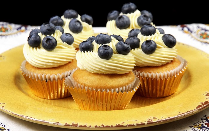 Blueberry cupcakes with cream frosting on a yellow plate