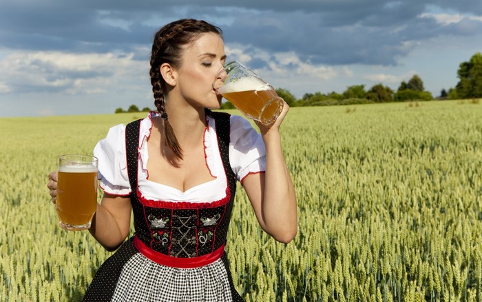 Woman in Dirndl drinking beer in a field