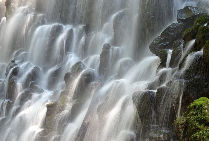 Water flowing over mossy rocks in a waterfall