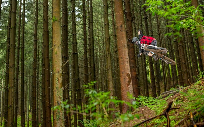 Mountain biker jumps through a dense forest