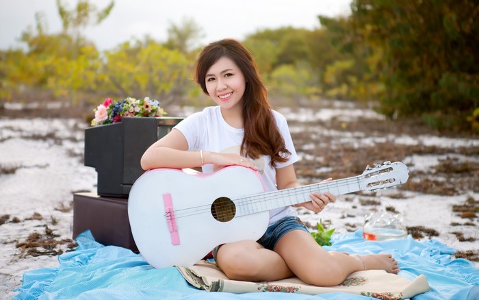 Asian woman with brown hair playing guitar