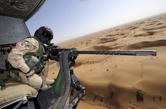 Soldier with GAU-21 M3M machine gun in a helicopter over a desert