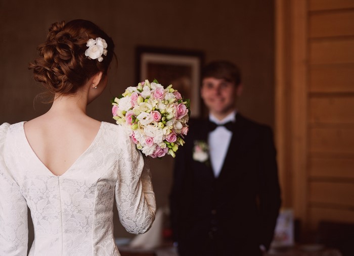Bride holding bouquet facing groom