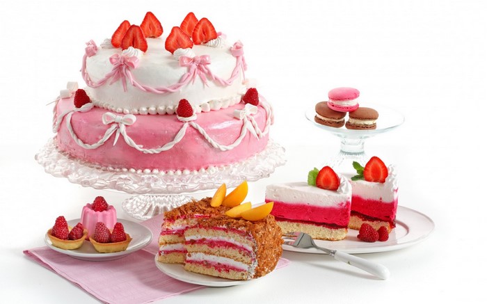 Assortment of pink and white cakes and pastries with strawberries