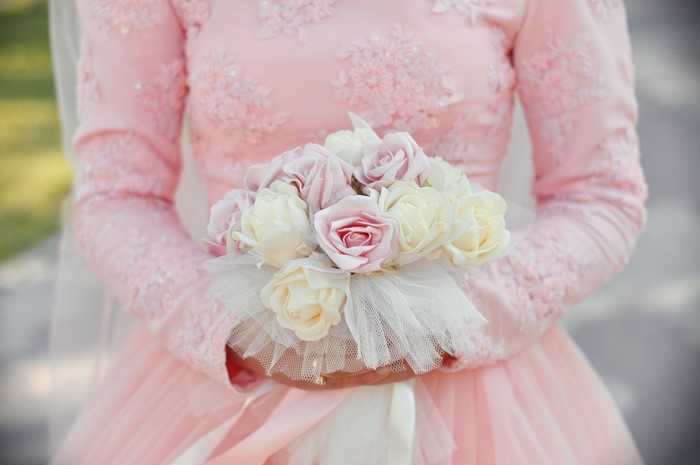 Bride in pink dress holding a bouquet of roses