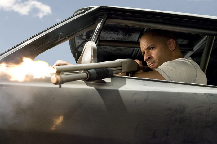 Vin Diesel firing a shotgun from a car