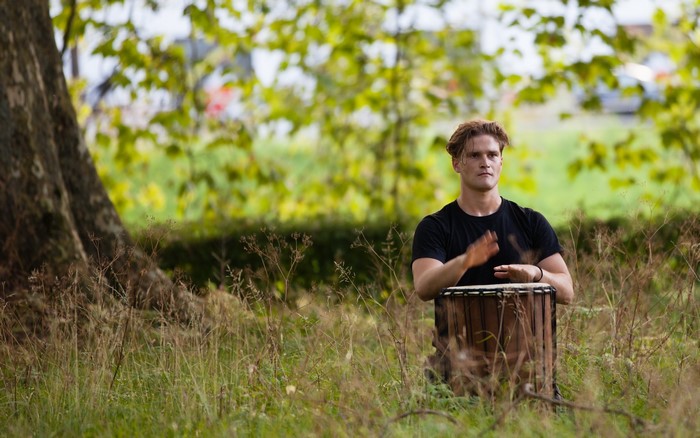 Man playing a drum in a grassy field