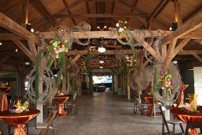 Barn interior decorated for an event with floral arrangements and lights