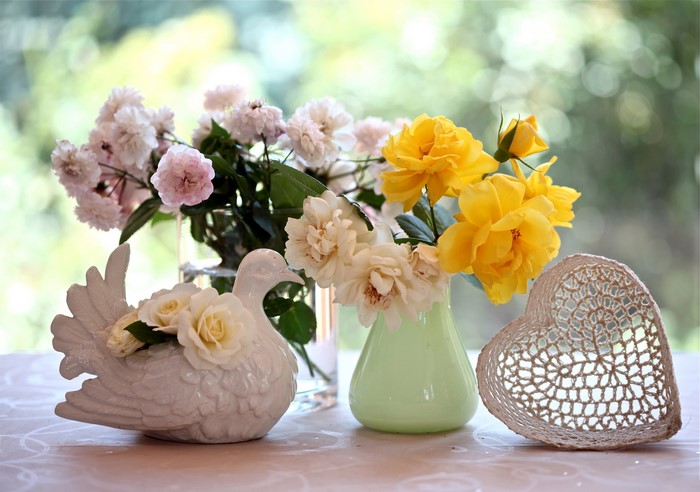White dove figurine with roses and yellow roses in vases