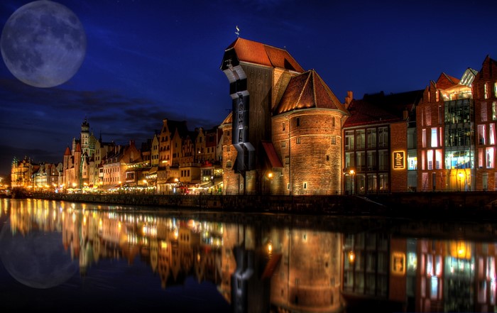 Gdańsk at night with a large moon over the river