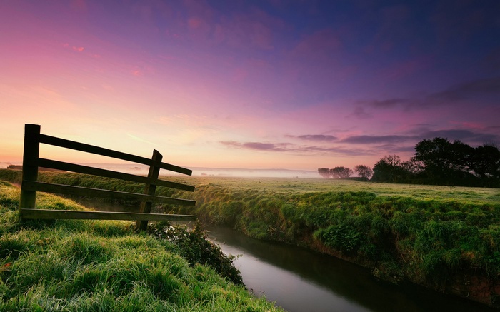 Wooden fence by a stream at sunrise