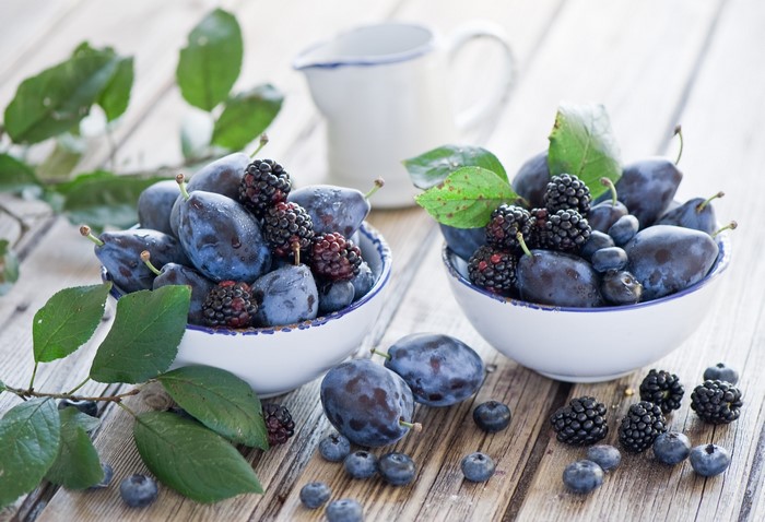 Plums and Blackberries in Bowls with Leaves