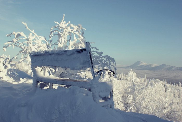 Snow-covered bench in a winter landscape in Russia