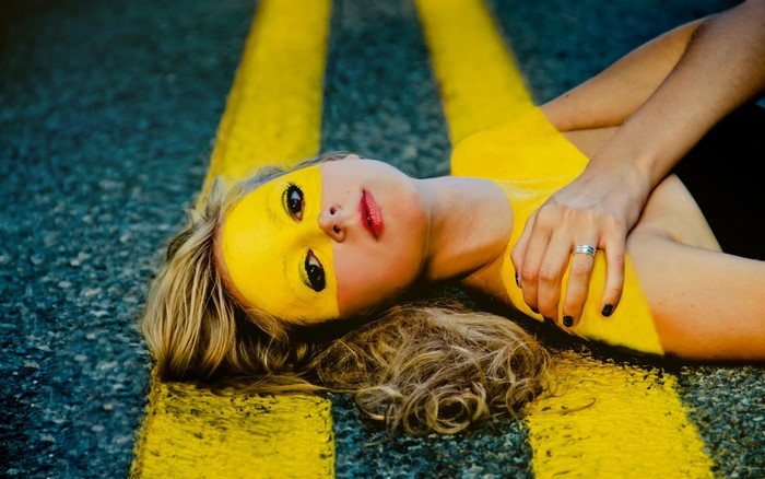 Woman with yellow face paint on road