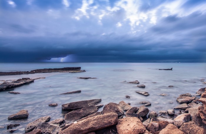 Sea coast with rocks and thunderclouds with lightning