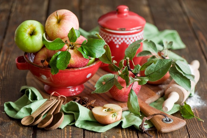 Still-life of apples in a red bowl with baking utensils