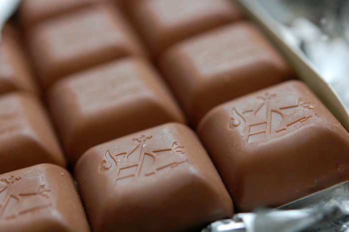 Close-up of milk chocolate squares with embossed logo