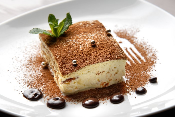 Tiramisu dessert with chocolate and mint on a white plate