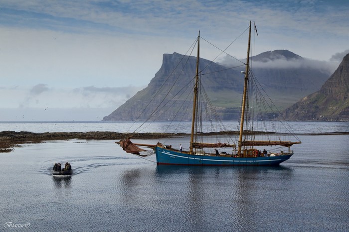 Blue sailing yacht near mountains in Faroe Islands