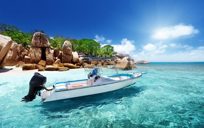 Boat anchored in clear turquoise water near rocky coast