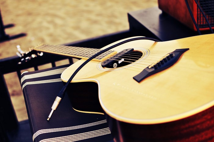 Acoustic guitar with cable on a striped chair