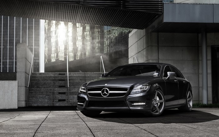 Dark Mercedes-Benz CLS parked by modern building stairs
