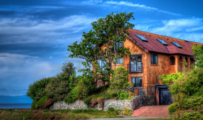Orange house with red roof and trees by the ocean