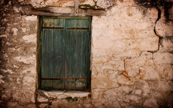 Old stone wall with a weathered green wooden window