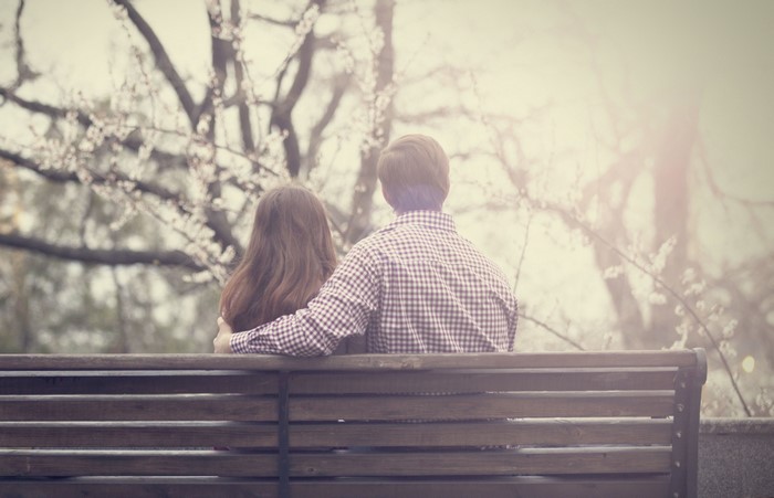Couple sitting on a bench in front of blooming trees