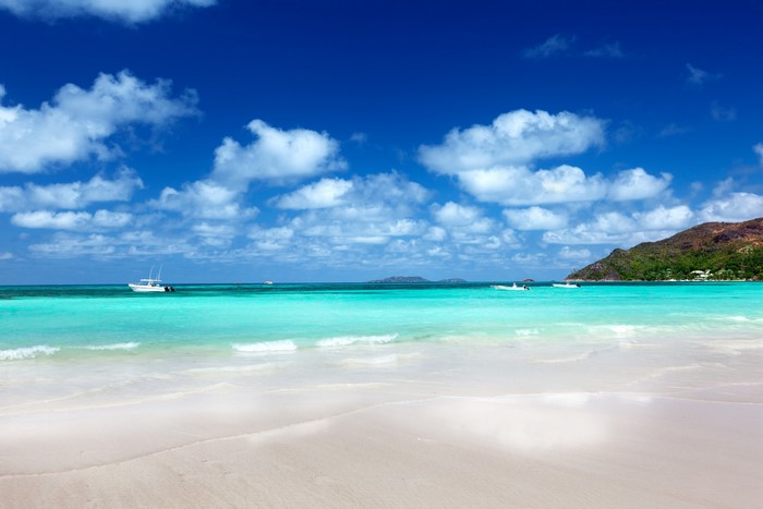Beach with turquoise water and boats under blue sky