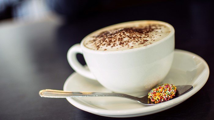 Cappuccino in a white cup with a sprinkle-covered spoon