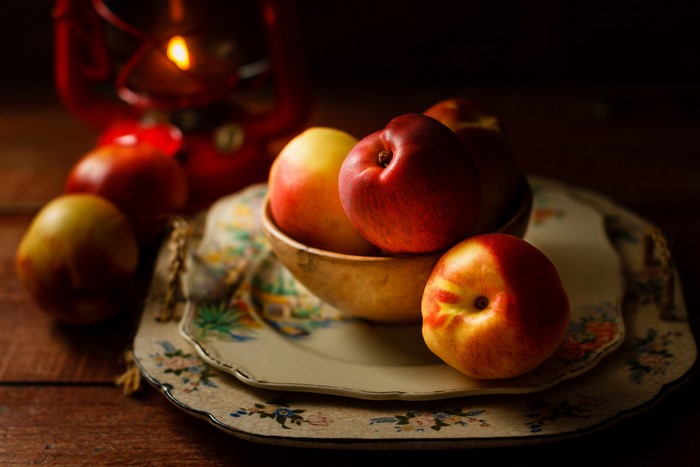 Still life of nectarines and apples with a lantern