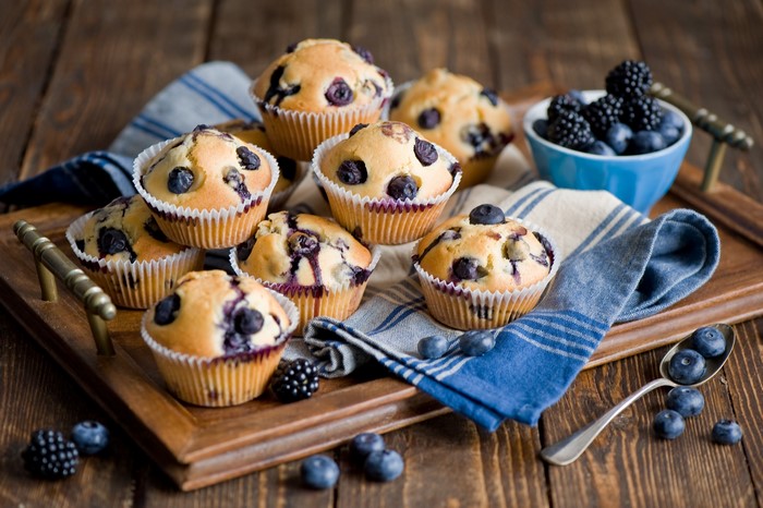 Blueberry and blackberry muffins on a wooden tray