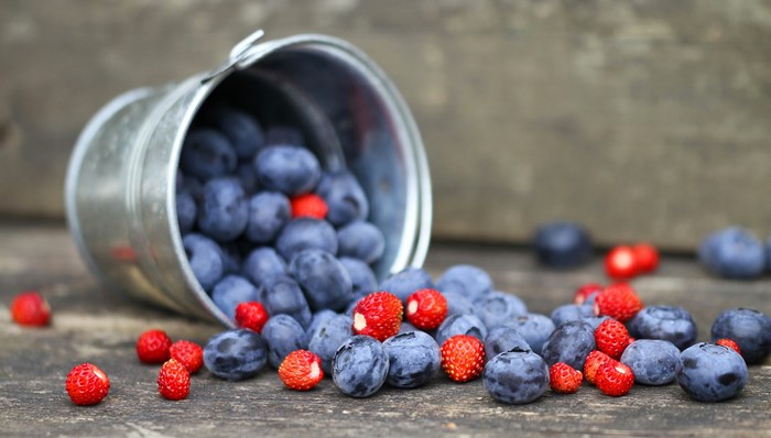 Blueberries and strawberries spilling from a bucket
