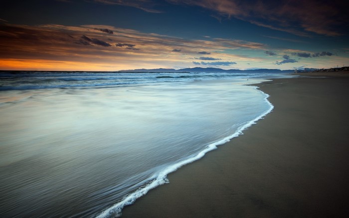 Sunset over a sandy beach with ocean waves
