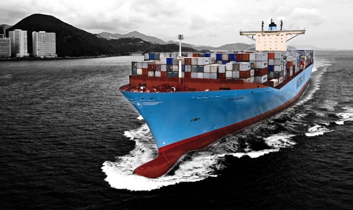 Maersk container ship sailing near a city