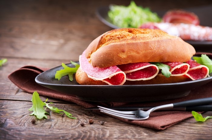 Sandwich with salami and arugula on a plate