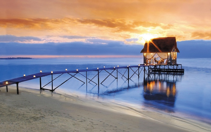 Overwater bungalow at sunset with a pier